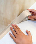 Peel And Stick Caulk Tape For Tub And Shower Waterproof Seal Strip being applied by hand along a wall edge, 1.5 inch width.