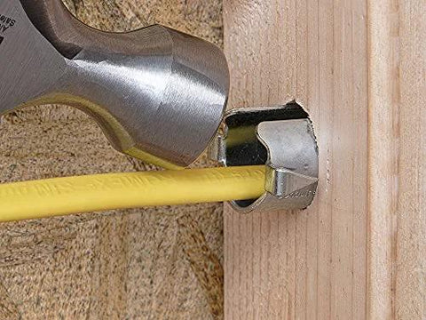 Metal nail guard for wire protection installed on a wooden stud with a yellow electrical cable, hammer nearby