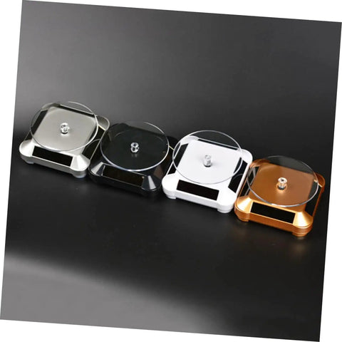 Solar Powered Rotating Jewelry Display Stand With Built In Kickstand in silver, black, white, and gold colors on a black background.