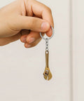Hand holding Adjustable Wrench Keychain For Women With Realistic Copper Color Mini Tool Charm, industrial style for keys and bags.
