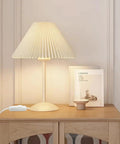 Table lamp with pleated shade and full range inline dimmer switch for dimmable LEDs and incandescents on wooden shelf.