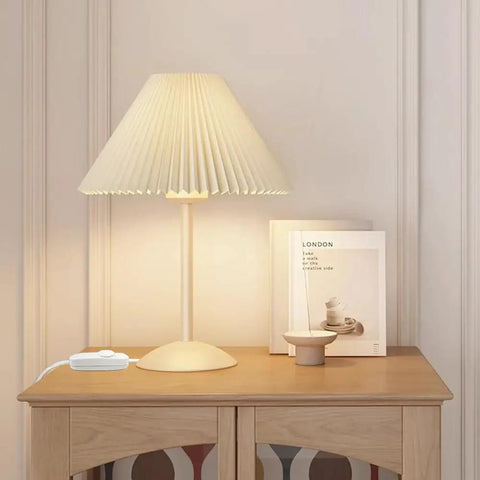 Table lamp with pleated shade and full range inline dimmer switch for dimmable LEDs and incandescents on wooden shelf.