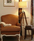 Vintage Teak Wood Tripod Floor Lamp with Chrome Finish 55 Inch Tall Nautical Inspired Rustic Modern Home Decor for Living Room or Den Shade Not Included Durable Steel and Aluminum Construction Unique Gift Idea next to a brown armchair