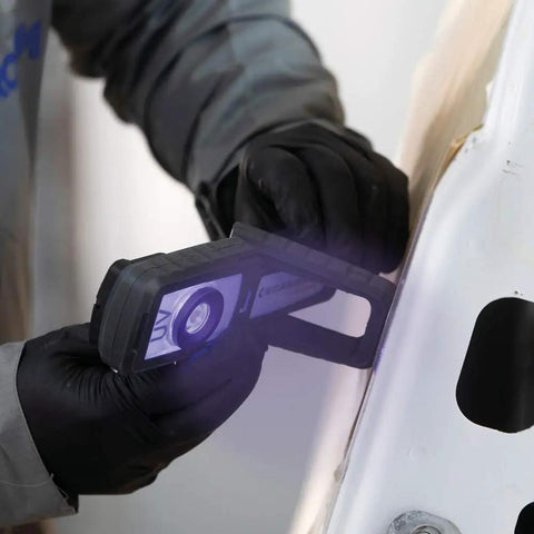 Person using rechargeable LED UV curing light for small and medium areas on metal, handheld lamp with hook and magnet shown in action.