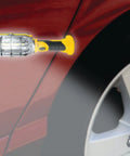 Ultra Bright Cordless LED Work Light With Magnetic Base 500 Lumens Battery Powered AA Batteries Included Handy On The Go Compact Handheld Flashlight attached to car with magnetic base, illuminating wheel area for repairs