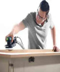 Man using 5-Inch Random Orbital Sander ETS EC 125/3 EQ-Plus Brushless EC TEC Motor with ergonomic grip on wooden surface.