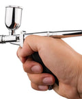 Heavy Duty Gravity Feed Dual Action Pistol Grip Airbrush With Adjustable Flow Control held in hand for detailed painting.