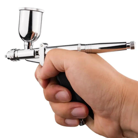 Heavy Duty Gravity Feed Dual Action Pistol Grip Airbrush With Adjustable Flow Control held in hand for detailed painting.