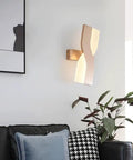 UPRENXIAO Modern Minimalist Nordic Led Wall Sconce Wavy Twisted Design Baked illuminating a living room wall beside a couch.
