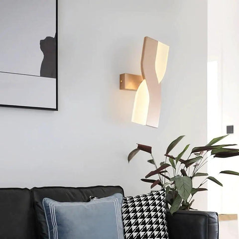 UPRENXIAO Modern Minimalist Nordic Led Wall Sconce Wavy Twisted Design Baked illuminating a living room wall beside a couch.