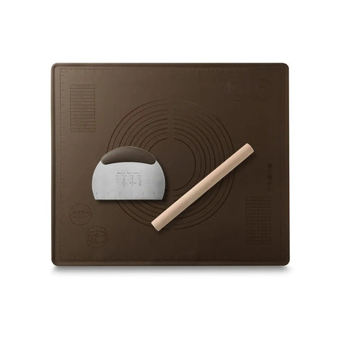 Brown silicone baking mat with an angled metal dough scraper and wooden rolling pin placed on top.