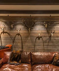 Interior view of a rustic living room with a brown leather sofa, weathered wood wall, and deer skull decor.