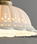 Ceramic Wall Sconce, 9 Inch Brass Vintage Light with floral cutout white porcelain lampshade showcasing warm glow.