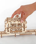 Tram With Rails 3D Puzzle Kit, Self Propelled Mechanical Wooden Model For Adults And Kids, Hands On Learning Mechanics, Build It, And Watch This Tiny Vehicle Cruise Rails. Wooden tram model on rails with hand, showing self-assembly mechanism.
