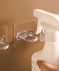 Heavy Duty Adhesive Wall Hooks 30 Pack Straight Up No Drill Setup For Bathroom Kitchen Storage Waterproof Plastic holding a spray bottle.