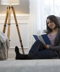 Woman sitting on floor reading next to lamp, cozy living room setting