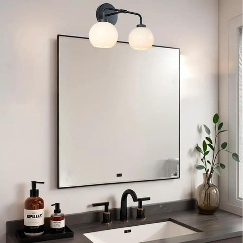 Double Glass Globe Wall Sconce, 17 Inch Sleek Modern Design in matte black above mirror in bathroom with vanity sink