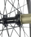 Close-up of Beast 50mm Carbon Basalt Braking Surface Clincher Road Wheelset 700c hub detail with spokes and matte 3k finish.