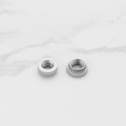 Pack Of Knurled Self Clinching Nuts M3 M4 M5 M6 M8 Crafted From Solid 304 Stainless Steel Rivet Nut Fasteners side view on marble background.