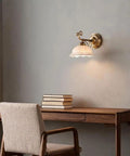 Ceramic Wall Sconce, 9 Inch Brass Vintage Light illuminating a desk with books, showcasing delicate floral shade and antique brass finish.