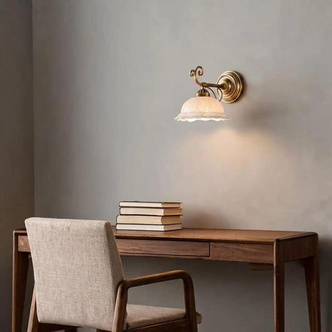 Ceramic Wall Sconce, 9 Inch Brass Vintage Light illuminating a desk with books, showcasing delicate floral shade and antique brass finish.
