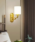 Solid Brass Wall Sconce With Smooth White Glass Shade Modern E27 Light Fixture beside a bed for ambient lighting in a modern bedroom.