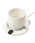 Slick Aluminum Coffee Cup Warmer With Smart Touch Controls And Automatic Shutoff Keeps Your Daily Brew Piping Hot At Fifty Five Degrees Zero Stress Compact Heated Desk Coaster on a table with a white mug.