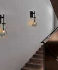 Black Raindrop Glass Wall Sconce With On Off Switch Sleek Modern Vanity Light Fixture illuminating hallway stairs for ambience.