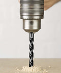 1/4-inch metal twist drill bit drilling into wood with sawdust.
