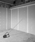 Micro Laser Distance Meter With Bluetooth Sync And Tilt Sensor placed in unfinished room, measuring angles with a clear backlit screen.