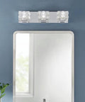 3 Light Sleek Chrome Integrated LED Vanity Light With Clear Cube Glass installed above a bathroom mirror on a blue wall