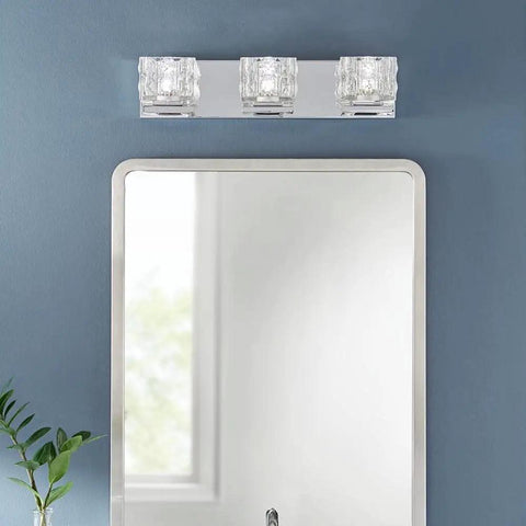 3 Light Sleek Chrome Integrated LED Vanity Light With Clear Cube Glass installed above a bathroom mirror on a blue wall