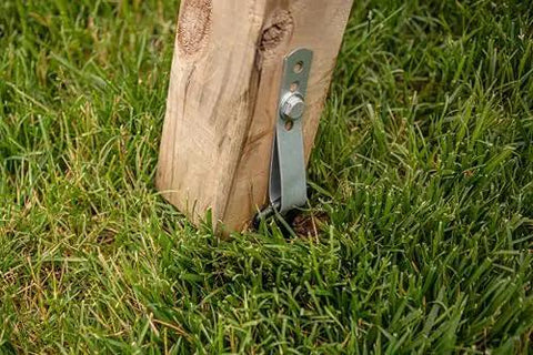 Heavy-duty steel anchor securing wooden swing set post for stability and safety, part of Playset Anchor Kit For Swing Sets Heavy Duty Ground Anchors That Keep Your Set Rock Solid Stationary And Safer For Outdoor Fun Easy Install Swing Set Hardware To Secure Play Equipment And Protect Your Kids