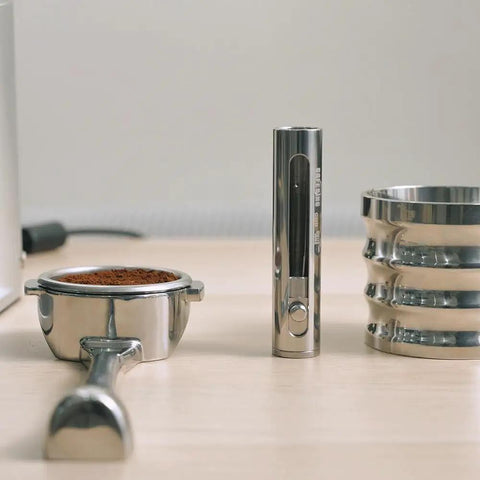 Premium Retractable Espresso WDT Tool All Stainless Steel Coffee Distribution Needle next to portafilter filled with grounds.