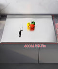 Front view of stainless steel kitchen cutting board, 40×30 cm, on a counter with knife and peppers