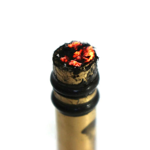 Close-up of Compact Air Compression Fire Starter With Durable Metal Body showing glowing embers at the tip for outdoor use.