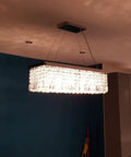 Ultra Modern Crystal Chandelier With Rectangle Raindrop Design in dining room setting, chrome finish, 31.5x10x9 inches.