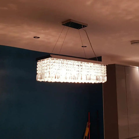 Ultra Modern Crystal Chandelier With Rectangle Raindrop Design in dining room setting, chrome finish, 31.5x10x9 inches.
