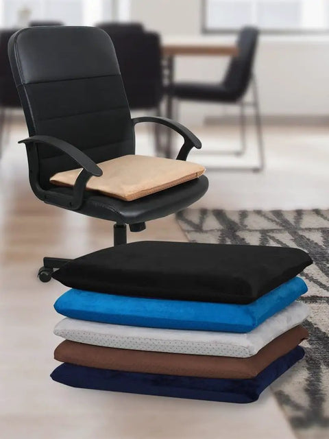 Stack of square 18x18 inch memory foam chair cushions in black, blue, gray, and brown, with one cushion on an office chair in a room.