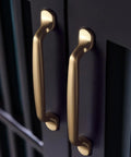Six Pack 5 Inch Center To Center Arch Cabinet Pulls In Champagne Bronze Finish made from zinc alloy installed on dark cabinets.