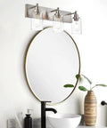 Dope Brushed Nickel Bathroom Light Fixture With Clear Glass Shade above round mirror in modern bathroom setting
