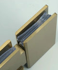 Close-up of Rock Solid Frameless Glass Shower Door Hinge For Modern Bathrooms in brushed gold finish with glass panels.