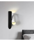 Rock Solid Black Iron Wall Sconce With Pivot Led Fixture And Chill Warm Glow Modern Minimalist Bedside Lighting mounted above bed.