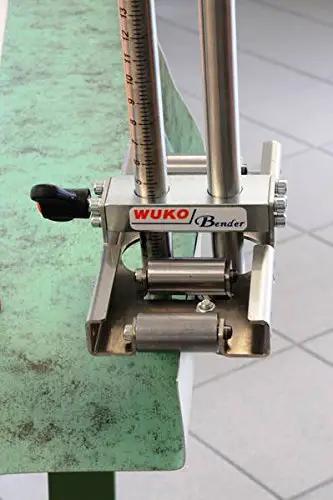 Close-up of Uni Bender 2204 Heavy Duty Metal Bending Tool for 90 Degree Angles with built-in 1/8 inch scale ruler on green surface.