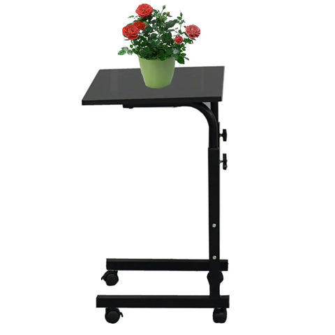 Rock Solid Adjustable Height Rolling Computer Desk With Smooth As Butter Locking Casters Portable Standing Laptop Table For Tight Quarters And Remote Work Setup In Glossy Black with potted flowers