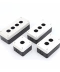 Automotive junction box with white lid and black base; four top knockout holes and corner mounting holes