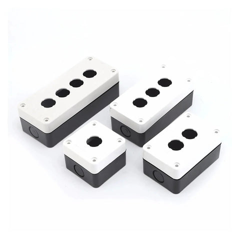 Automotive junction box with white lid and black base; four top knockout holes and corner mounting holes