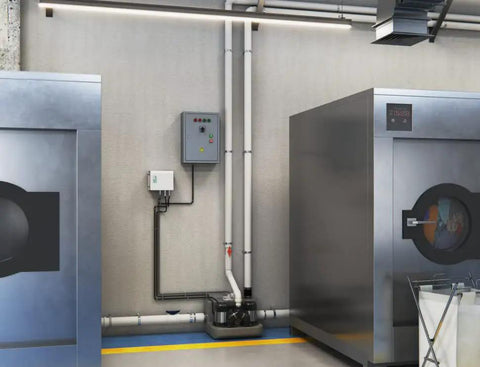 Sanicom 2 Commercial Wastewater Drain Pump Workhorse Badass system installed in a modern laundry facility with pipes and controls.