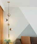 Lit Four Light Smoky Gray Glass Globe Pendant Light With Adjustable Cord And Gold Accents For Kitchen Island Bar Modern LED Chandelier Mid Century Industrial Ceiling Fixture in living room setting