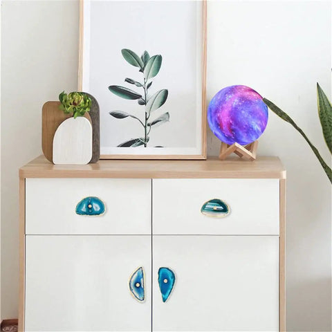 Real Deal Agate Stone Drawer Pulls With Sparkling Gold Plated Borders enhancing a modern dresser with a plant and decor.